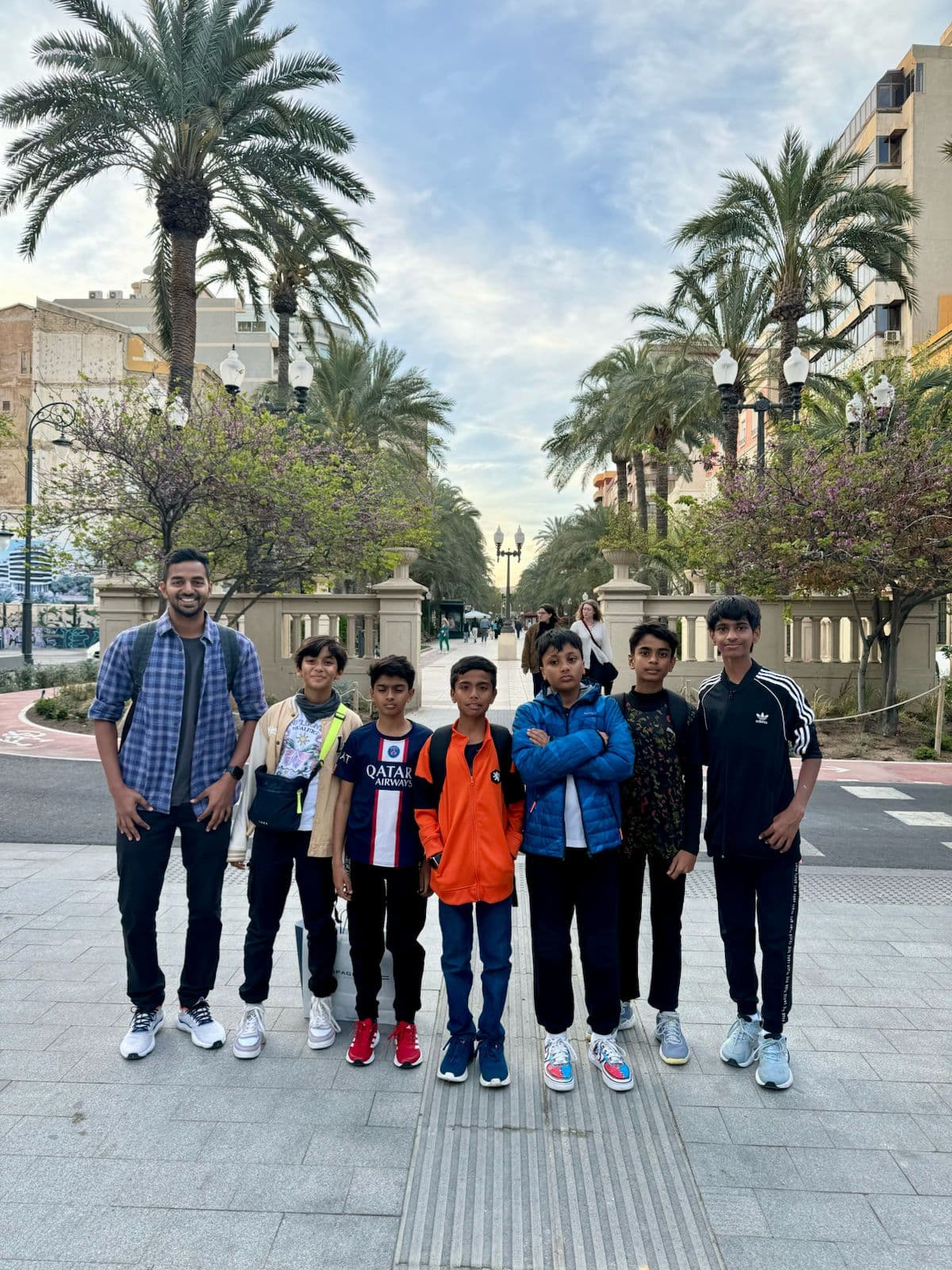 An Xdrona group with their chaperone on a palm-lined avenue in Spain.